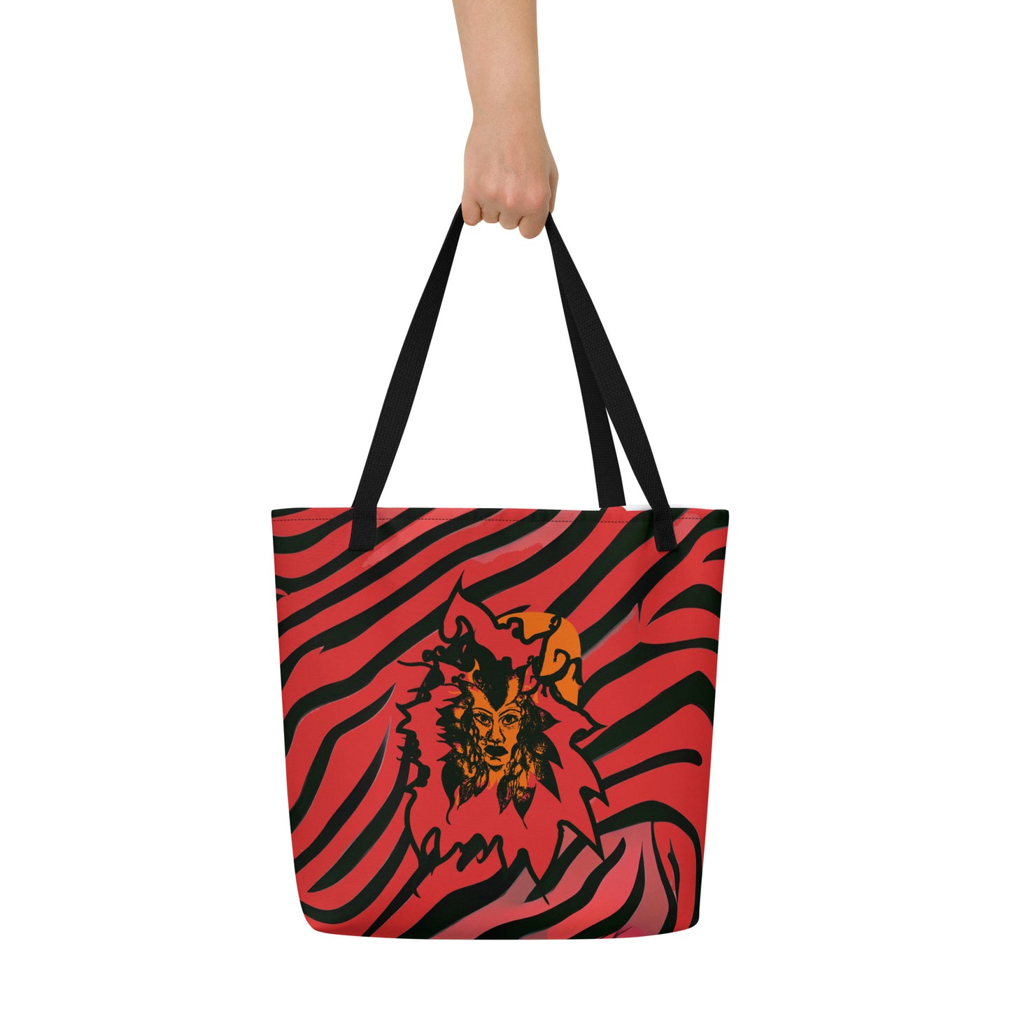 The hand holding a large red and black tote bag from Kloe Store featuring a bold artistic face design and abstract swirling patterns, with black straps, perfect for trendy and functional everyday use, detail view.