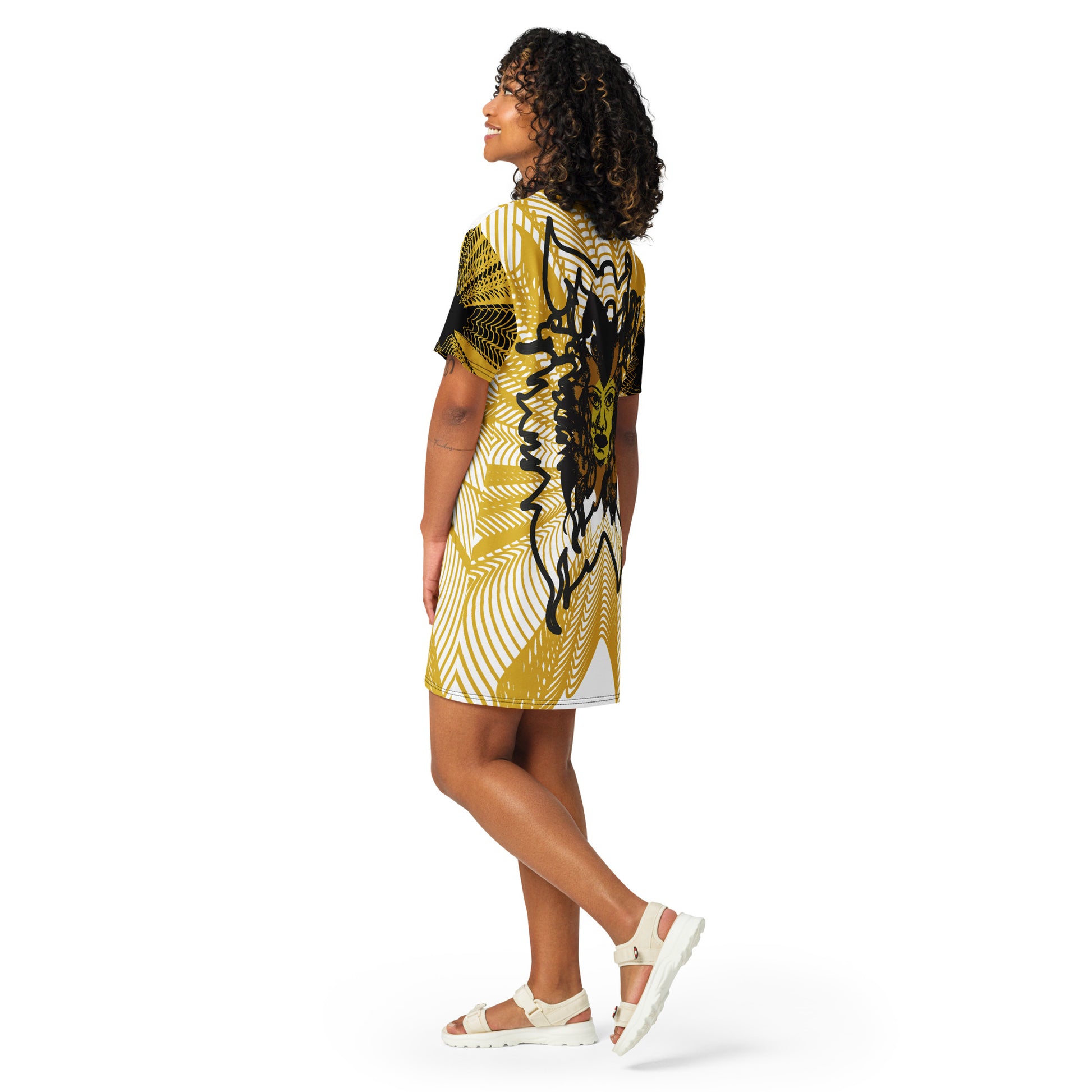 Back view of an all-over print K.L.O.E. t-shirt dress featuring a striking gold and white geometric radiating pattern, with a central hand-drawn black and gold and yellow face design, celebrating modern bohemian style and self-expression, worn by a model.