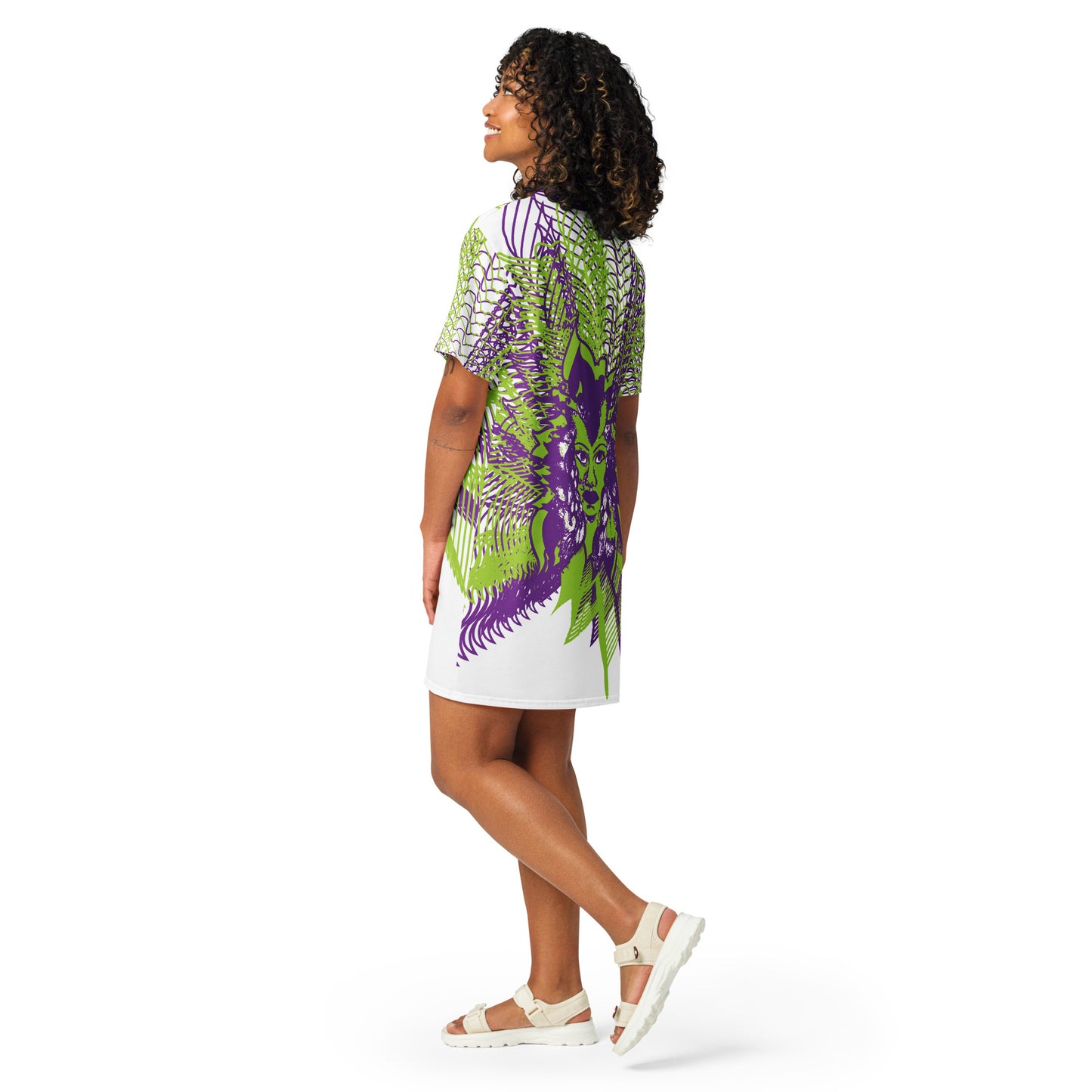 Back view of an all-over print K.L.O.E. t-shirt dress featuring bold purple and green geometric patterns radiating from a hand-drawn face design, representing individuality, self-expression, and modern bohemian style, worn by a model.