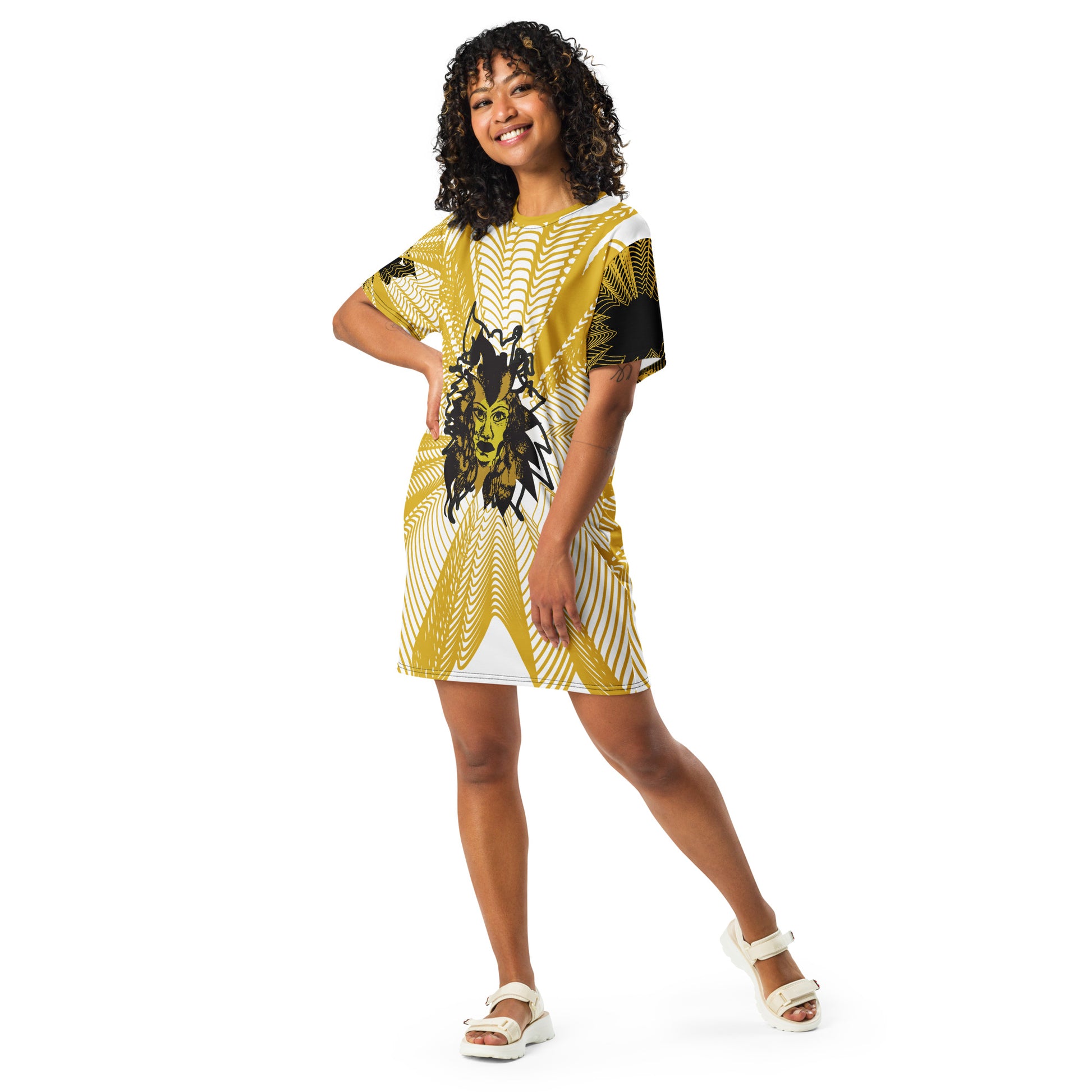 Front view of an all-over print K.L.O.E. t-shirt dress featuring a bold gold and white geometric pattern radiating from a central hand-drawn black and gold and yellow face design, embodying individuality, modern bohemian style, and self-expression, worn by a model.