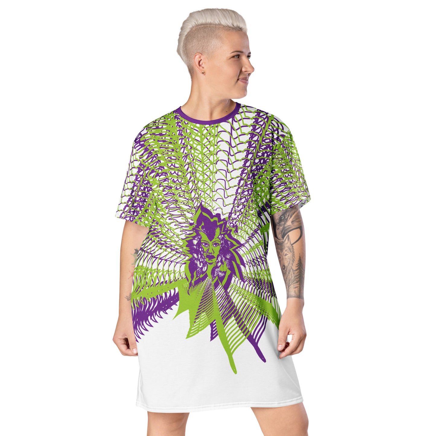 Front view of an all-over print K.L.O.E. t-shirt dress featuring vibrant purple and green geometric patterns radiating from a central hand-drawn face design, embodying individuality, self-expression, and modern bohemian fashion, worn by a model.