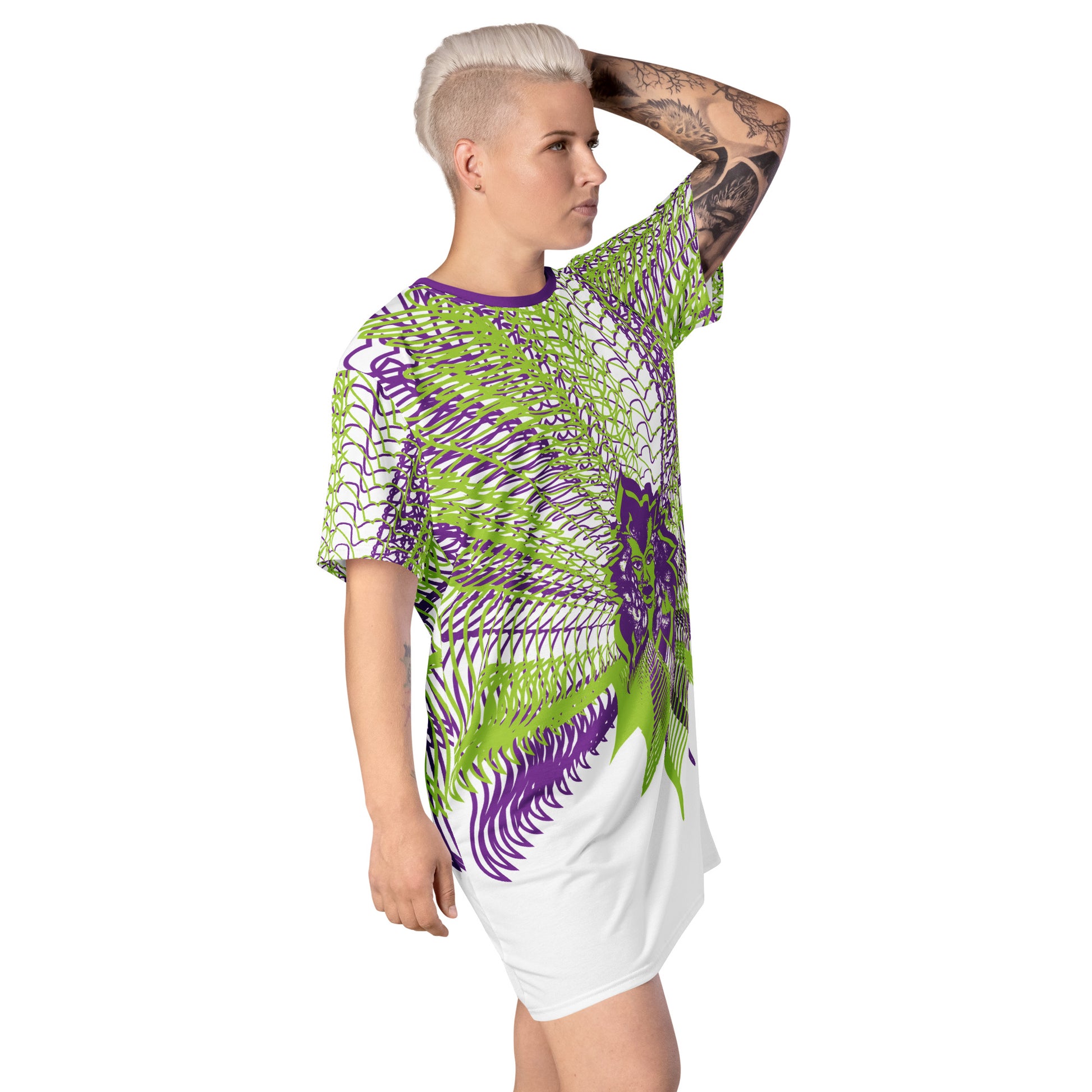 Front view of an all-over print K.L.O.E. t-shirt dress featuring vibrant purple and green geometric patterns radiating from a central hand-drawn face design, embodying individuality, self-expression, and modern bohemian fashion, worn by a model.