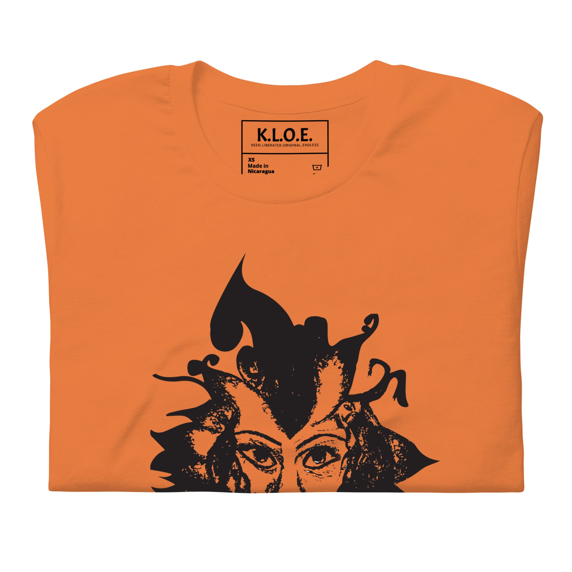 Detail view of orange K.L.O.E. T-shirt featuring a culturally inspired, hand-drawn black graphic of a bold, expressive face surrounded by intricate details, celebrating individuality and artistic self-expression in modern bohemian style fashion, the inside label view.