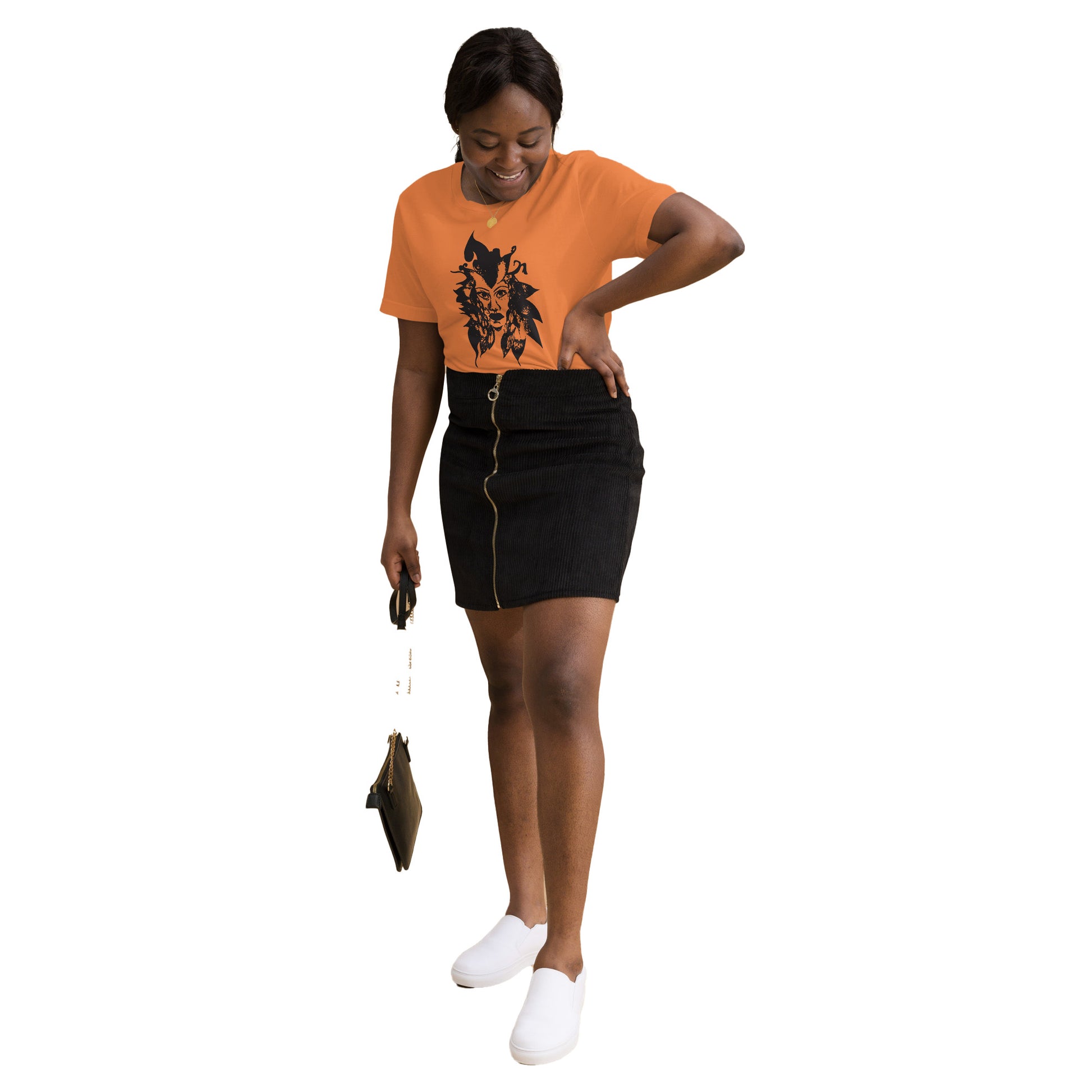 The model wearing orange K.L.O.E. T-shirt featuring a culturally inspired, hand-drawn black graphic of a bold, expressive face surrounded by intricate details, celebrating individuality and artistic self-expression in modern bohemian style fashion.