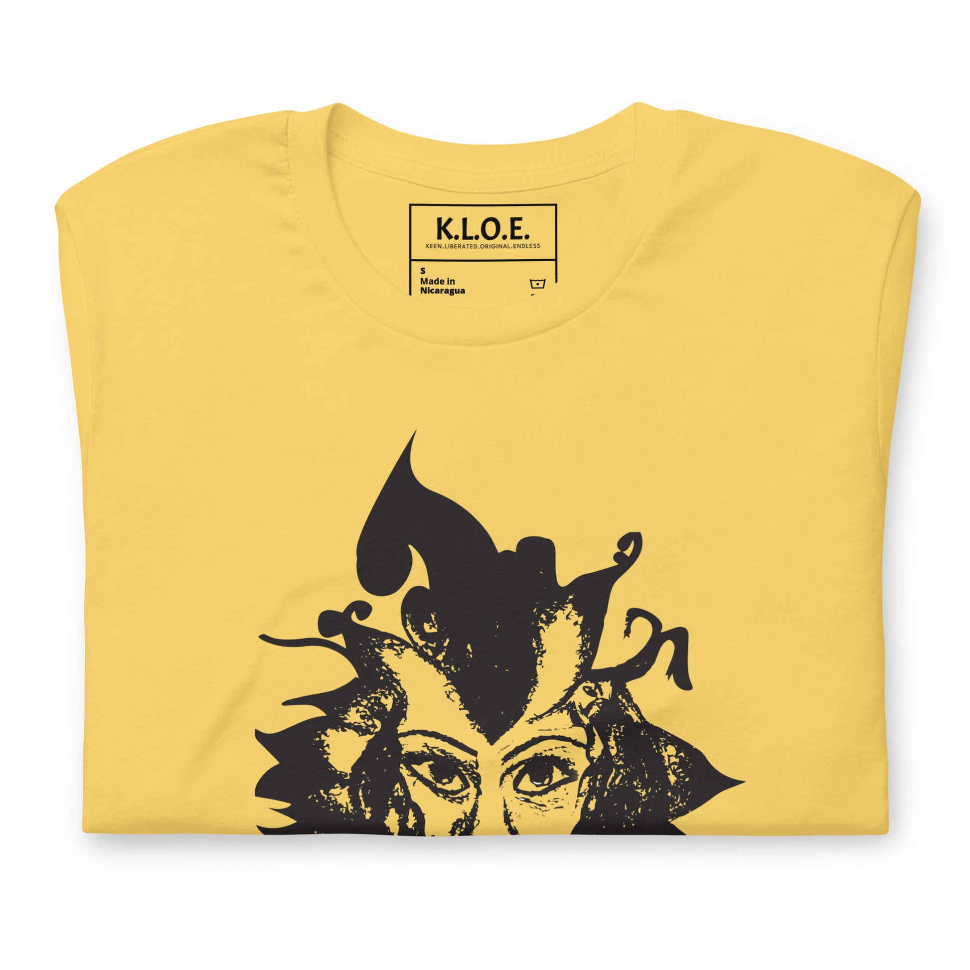 The view of the inside label of the yellow K.L.O.E. T-shirt featuring a culturally inspired, hand-drawn black graphic of a bold, expressive face surrounded by intricate details, celebrating individuality and artistic self-expression in modern bohemian style fashion.