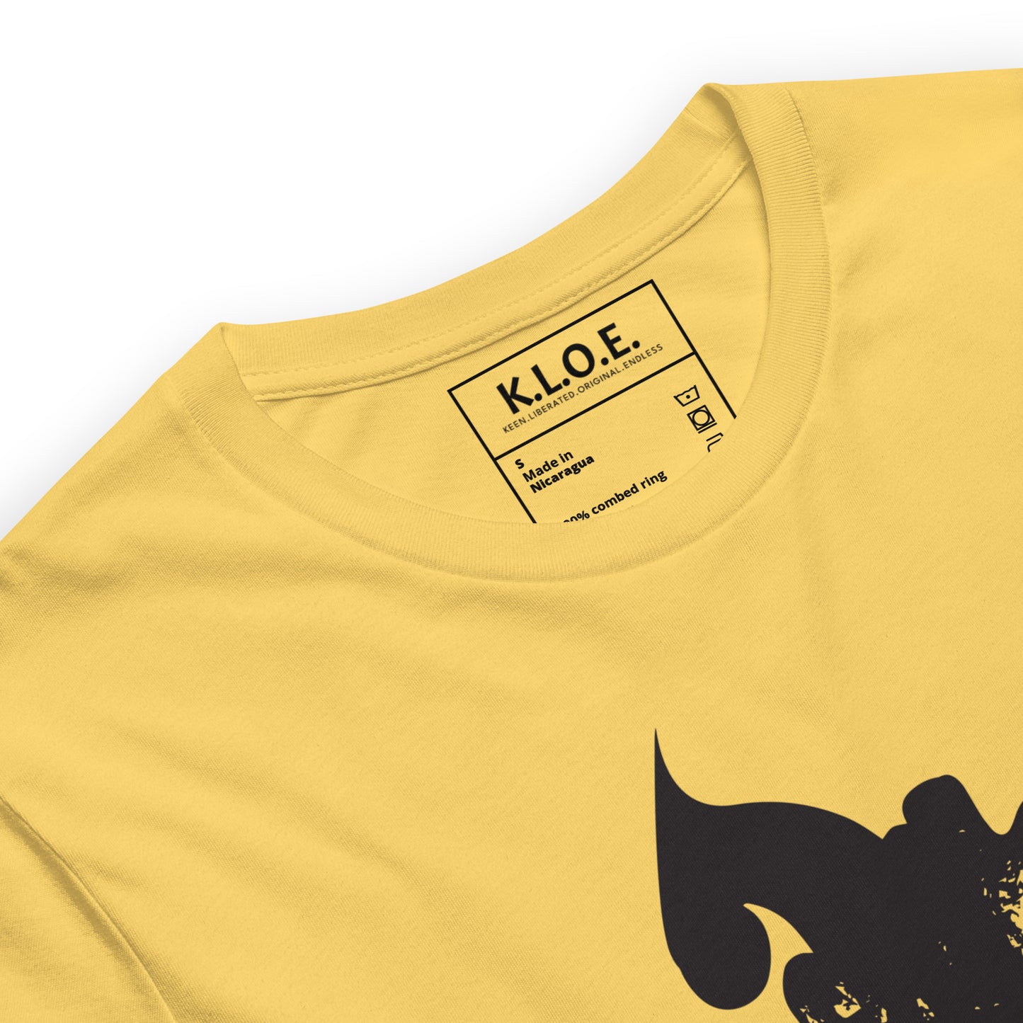 The view of the inside label of the yellow K.L.O.E. T-shirt featuring a culturally inspired, hand-drawn black graphic of a bold, expressive face surrounded by intricate details, celebrating individuality and artistic self-expression in modern bohemian style fashion.