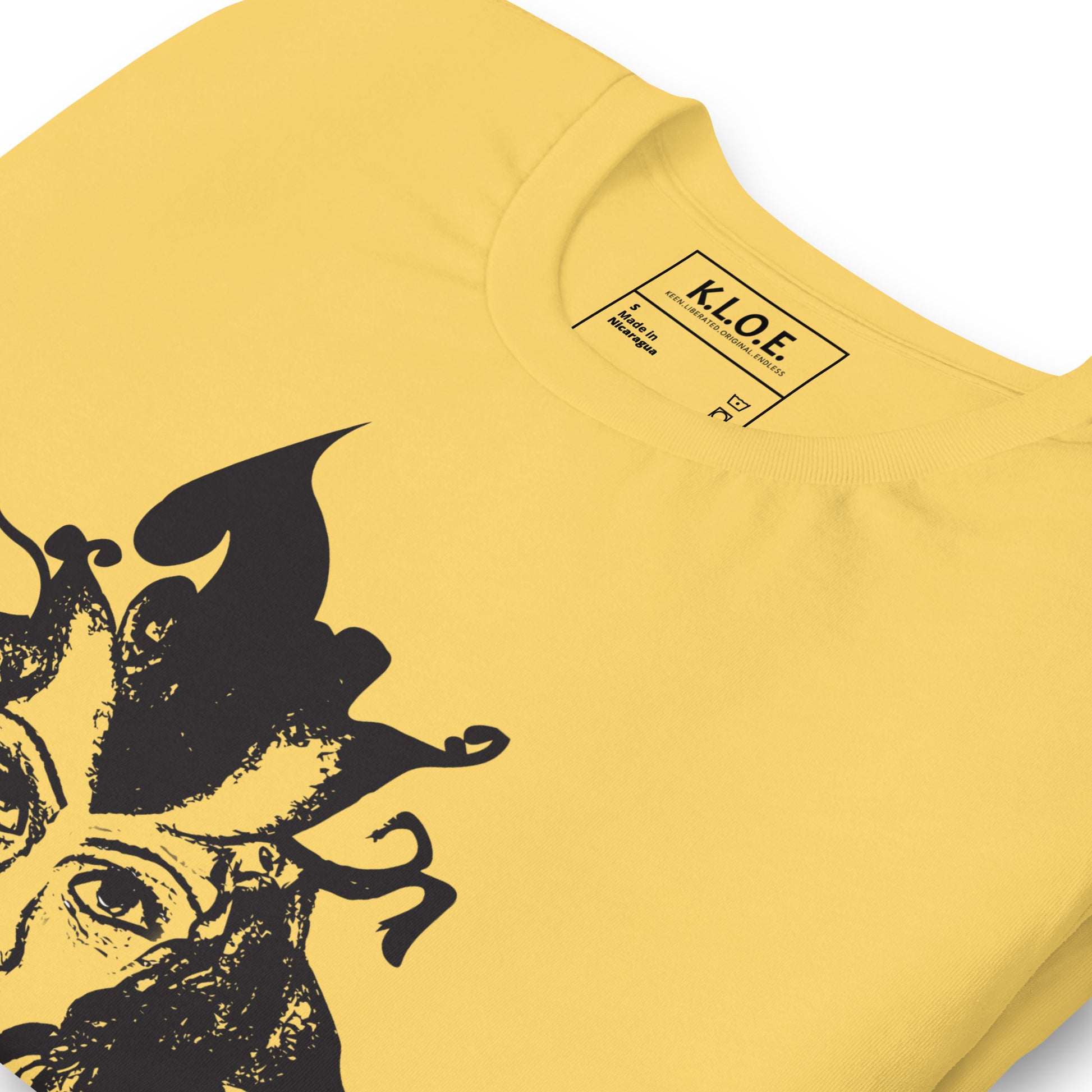 The view of the inside label of the yellow K.L.O.E. T-shirt featuring a culturally inspired, hand-drawn black graphic of a bold, expressive face surrounded by intricate details, celebrating individuality and artistic self-expression in modern bohemian style fashion.